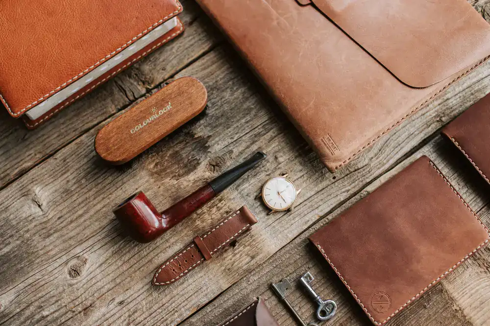 Assortment of handmade leather wallets, keychains, and belts arranged on a wooden table