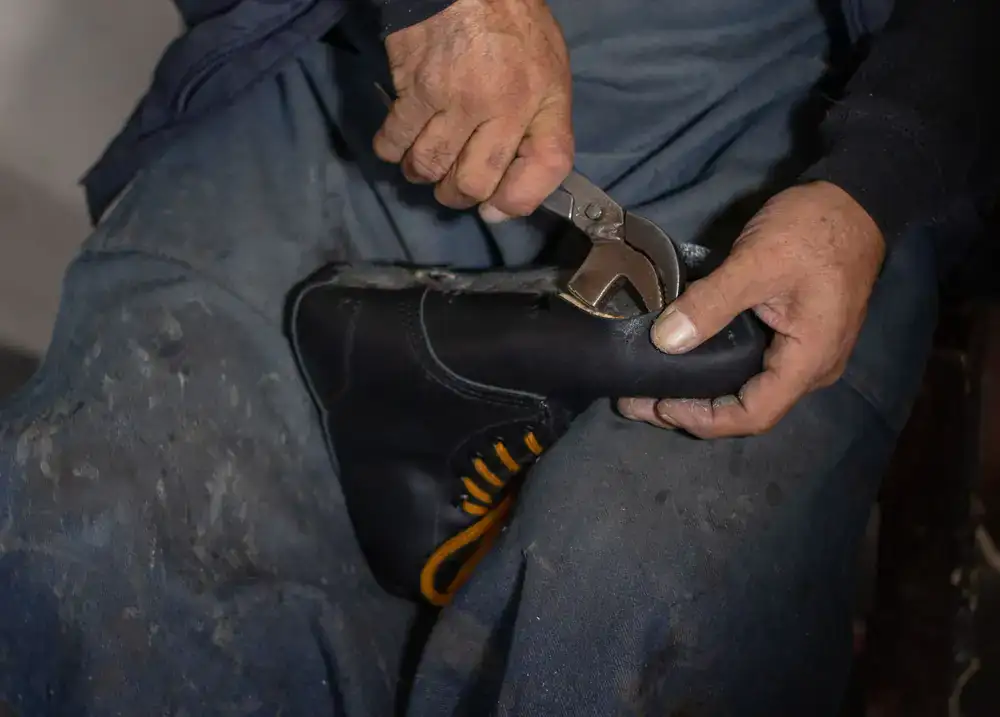 Close up of a cobbler's hands saddle-stitching thick leather